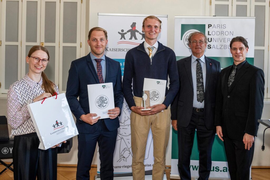 Fünf Personen bei einer Preisverleihung in Salzburg, zwei davon mit Urkunden.